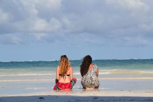 two girls sitting on the beach in Diani Beach