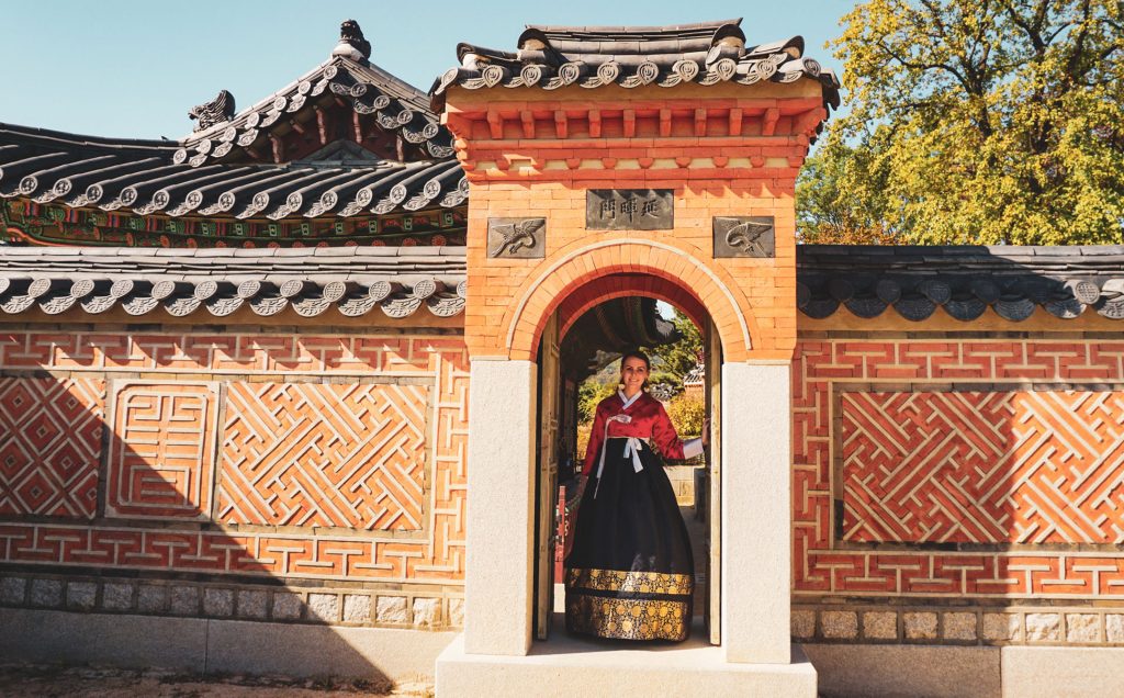 Woman in red and blue hanbok between wall